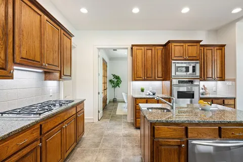 a kitchen with stainless steel appliances granite countertop a stove a sink and a microwave
