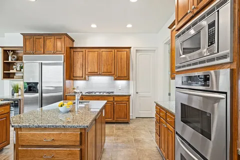 a kitchen with granite countertop stainless steel appliances and wooden cabinets