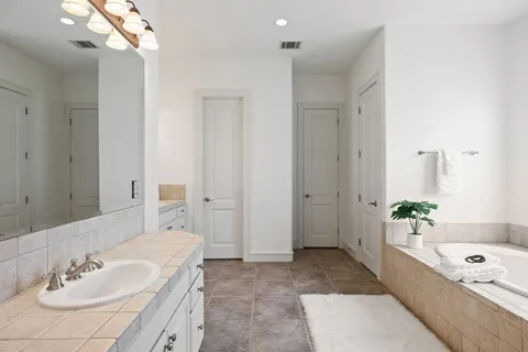 a bathroom with a tub a sink and a mirror
