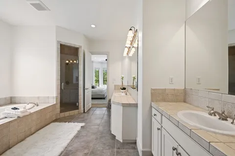 a spacious bathroom with a tub sink and mirror