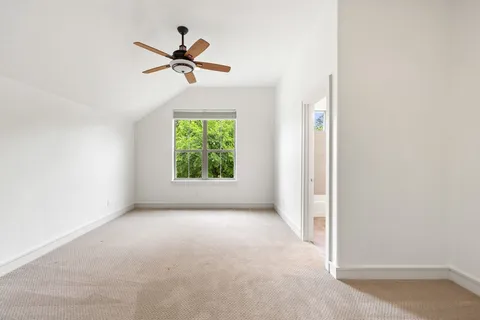 an empty room that has a window with a fan