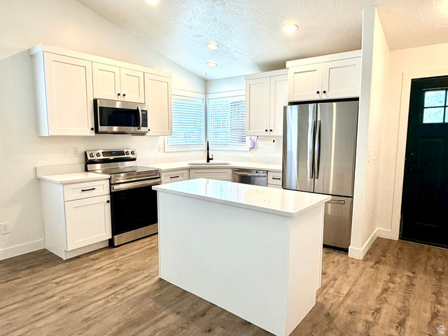 11895 Inauguration Road Draper, UT 84020 - Photo 3 of 10 Kitchen featuring white shaker cabinetry, stainless steel appliances, a center island, light countertops, and wood-finish flooring