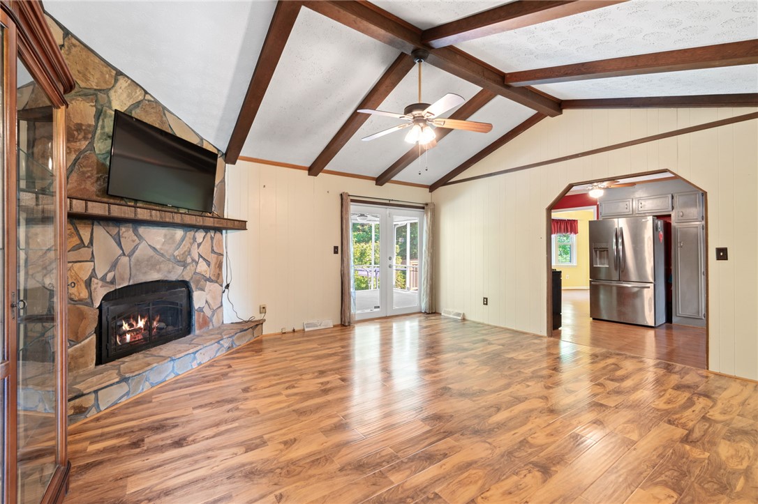 200 Echo Circle Easley, SC 29642 - Photo 10 of 35 A spacious living area features a stone fireplace, vaulted ceilings with exposed beams, and patio access.