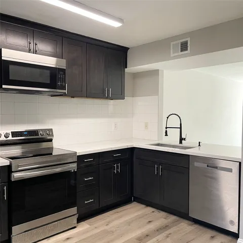 a kitchen with a sink and steel appliances