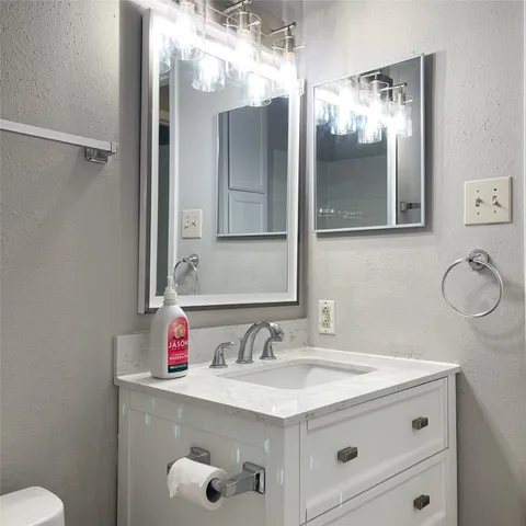 a bathroom with a granite countertop sink a toilet and a mirror