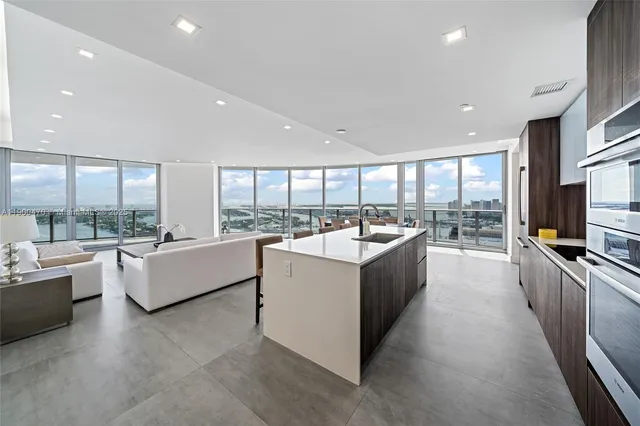 a large white kitchen with a large window and a counter space
