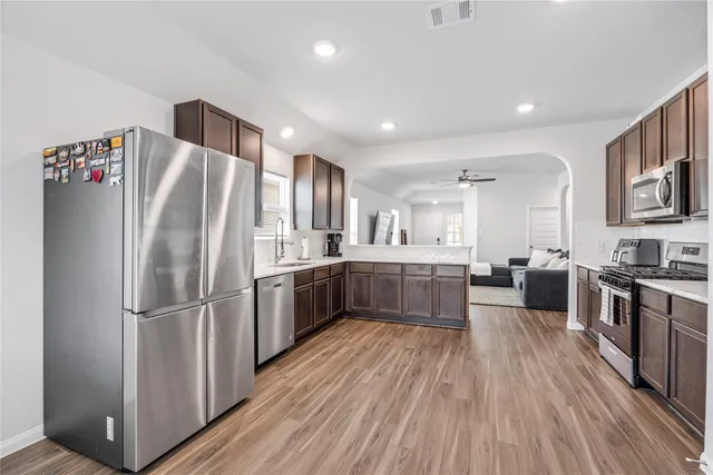 a kitchen with stainless steel appliances a refrigerator a sink dishwasher a stove top oven a counter space and wooden floor