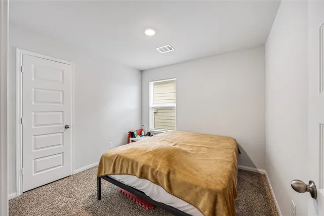 a bed sitting in a spacious bedroom next to a window