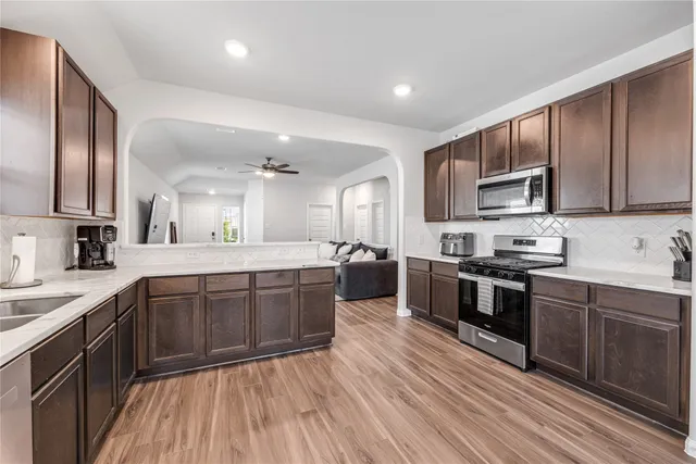 a large kitchen with stainless steel appliances wooden floors and wooden cabinets