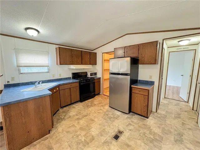 a kitchen with granite countertop a refrigerator and a stove top oven