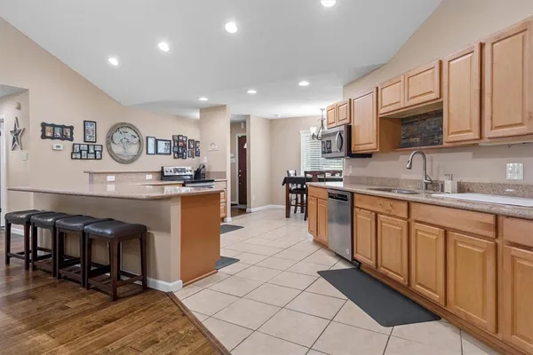 a kitchen with stainless steel appliances granite countertop a stove top oven a sink a dining table and chairs