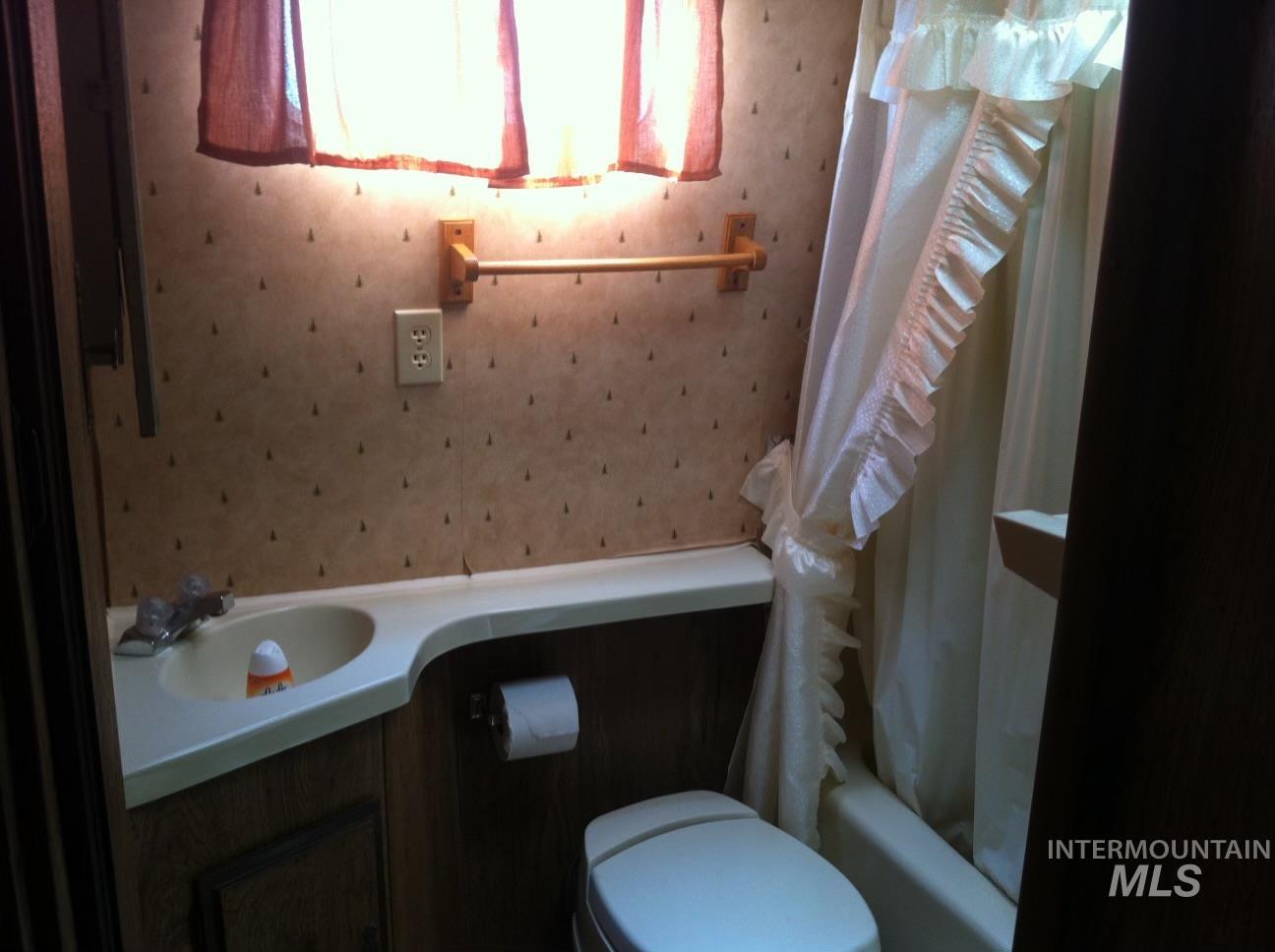 32214 Snake River Road Huntington, OR 97907 - Photo 23 of 31 Full bathroom with wallpapered walls, vanity, and shower / bathtub combination with curtain