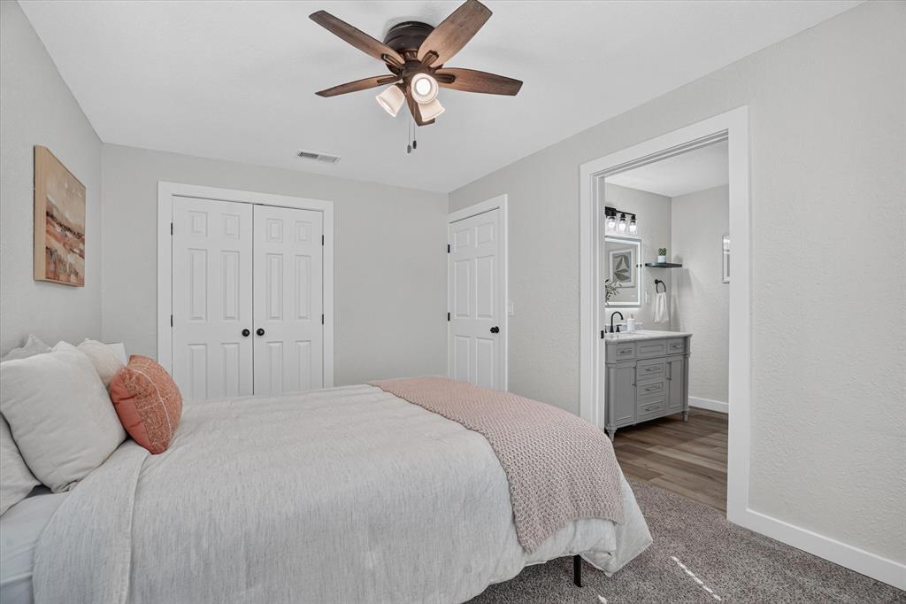 795 Meadow Road Springtown, TX 76082 - Photo 10 of 25 Ceiling fan with integrated lighting, dual bifold closet doors, light gray wall finish, and an adjacent bathroom with a vanity sink