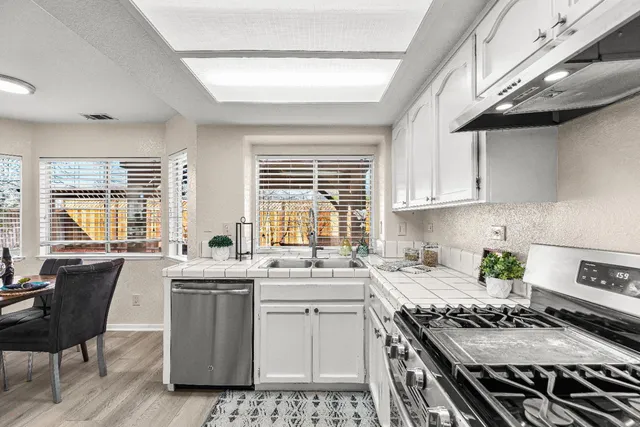 a kitchen with a stove a sink a window and dining table