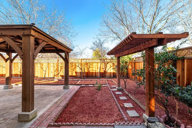 a view of patio with a table and chairs under an umbrella with a small yard