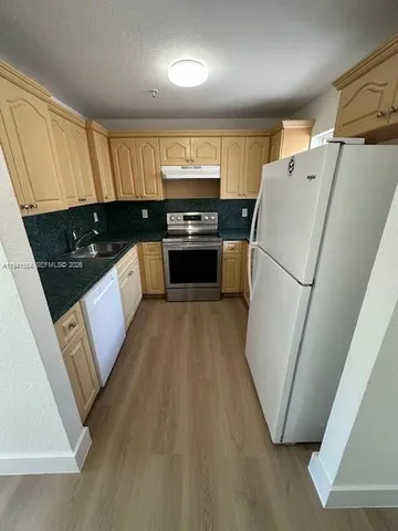 a kitchen with a refrigerator a stove a sink and a window