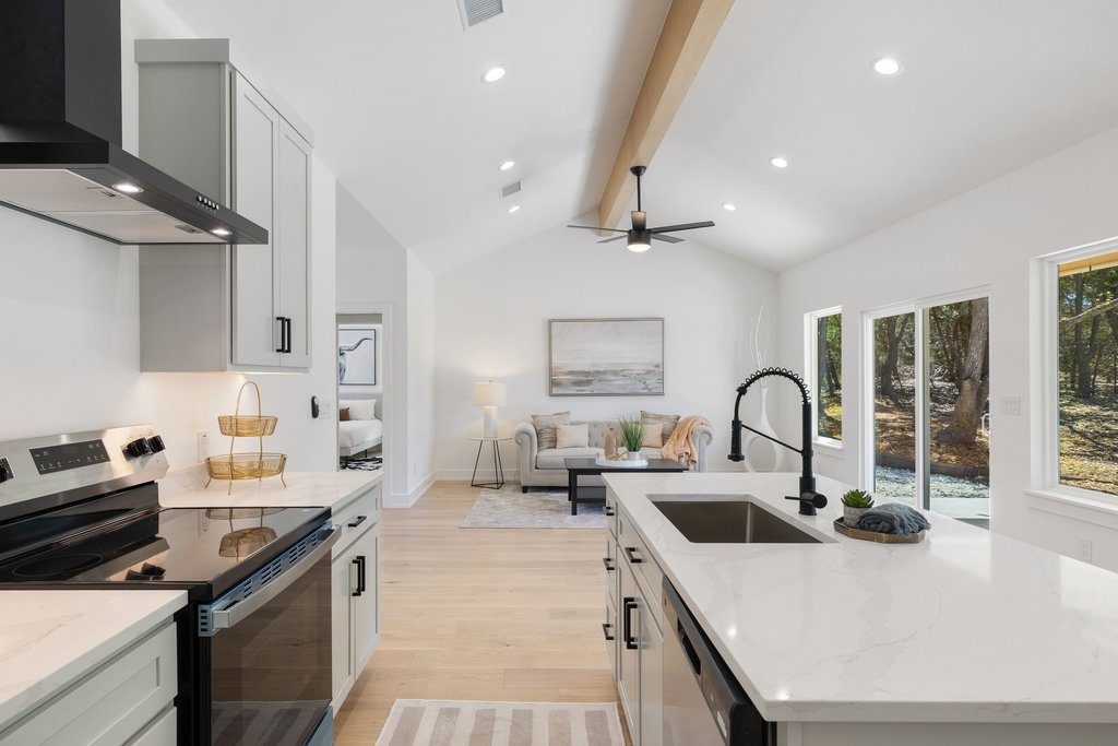 408 Rust Ranch Road Blanco, TX 78606 - Photo 33 of 34 Kitchen with stainless steel appliances, a center island with sink, light wood finished floors, open floor plan, and beamed ceiling