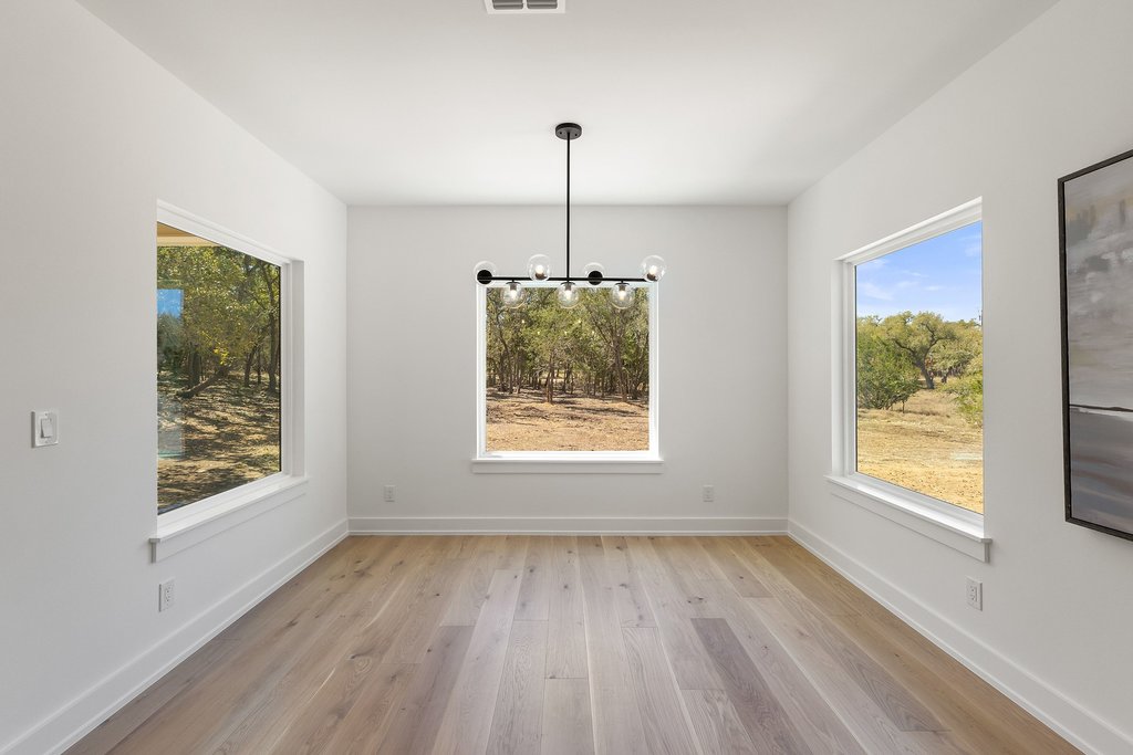 408 Rust Ranch Road Blanco, TX 78606 - Photo 11 of 34 Unfurnished dining area with light wood-style floors and hanging lights