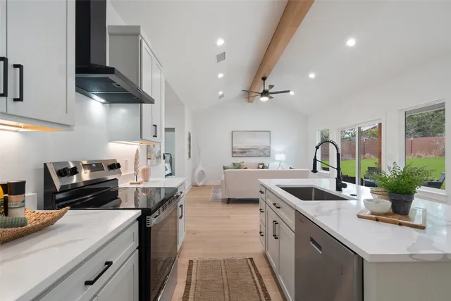 a kitchen with stainless steel appliances granite countertop a sink a stove and a wooden floors
