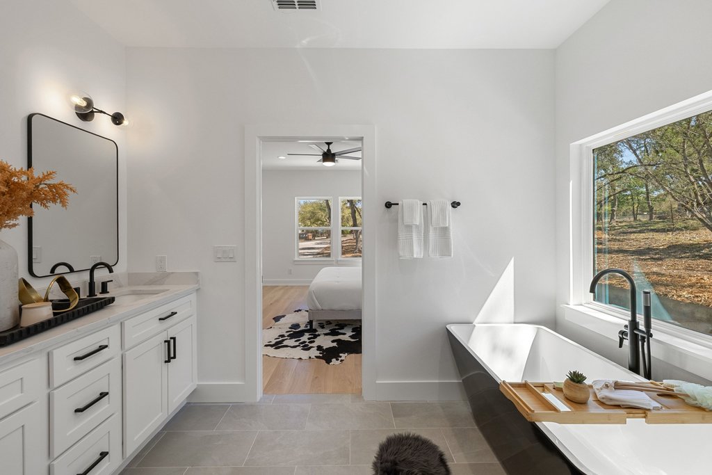 408 Rust Ranch Road Blanco, TX 78606 - Photo 14 of 34 Ensuite bathroom featuring vanity, a freestanding tub, light tile patterned floors, and a ceiling fan