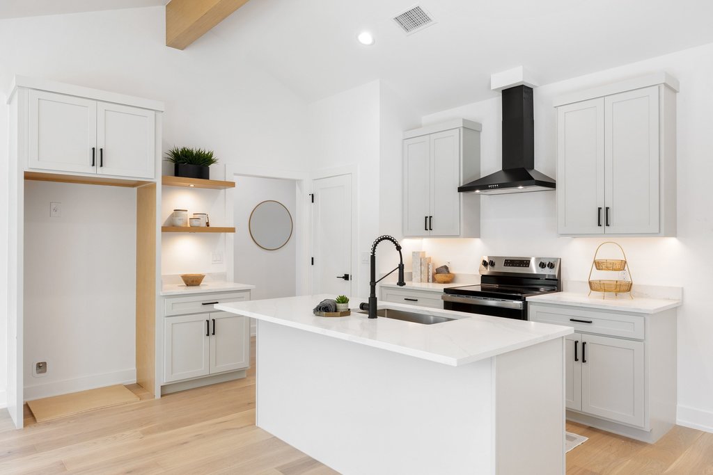 408 Rust Ranch Road Blanco, TX 78606 - Photo 9 of 34 Kitchen with electric range, light wood-type flooring, a center island with sink, white cabinetry, and light stone counters