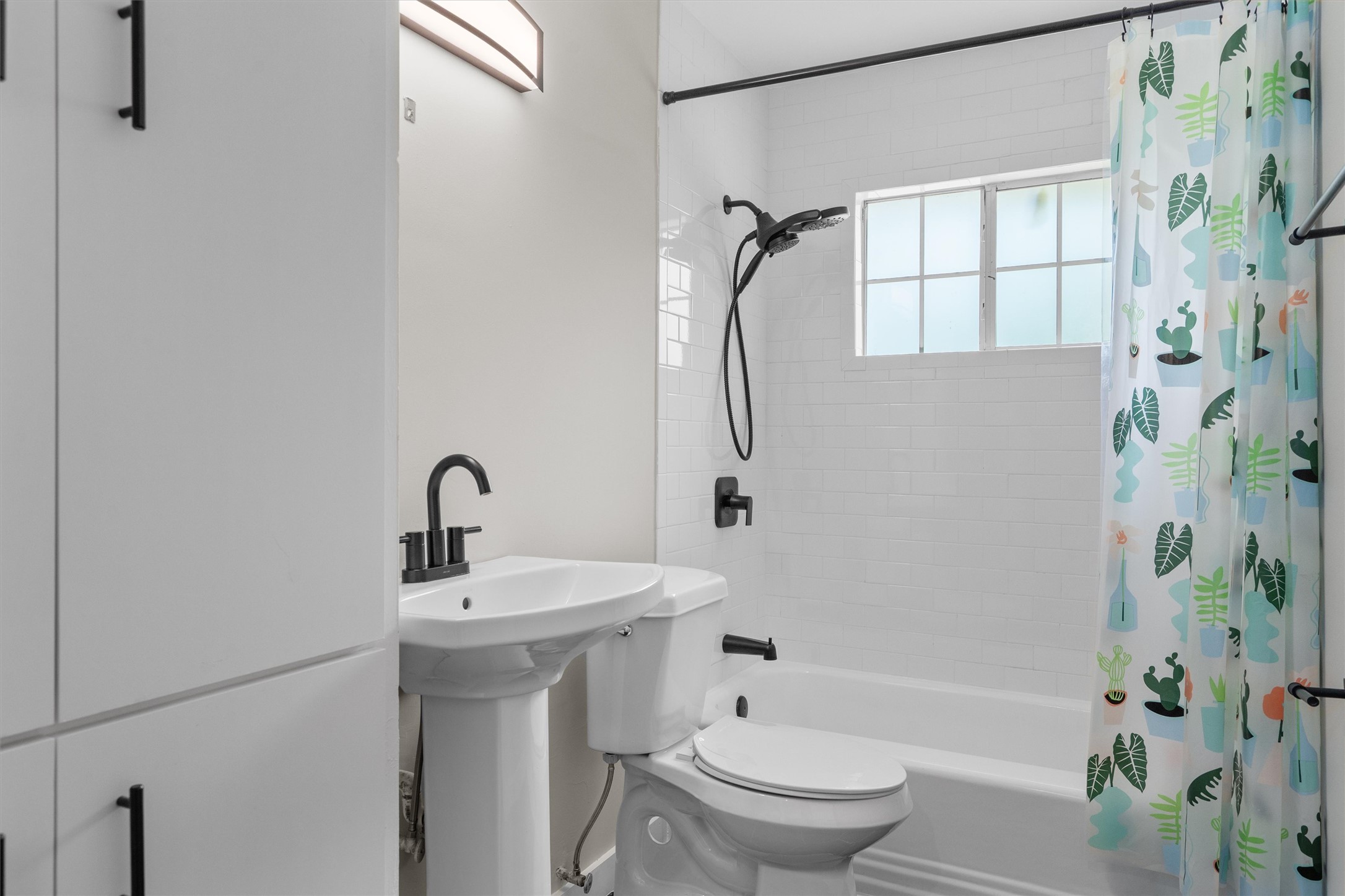 7707 Robalo Road Austin, TX 78757 - Photo 23 of 33 A well-appointed bathroom features a pedestal sink and sleek black fixtures against subway tile.