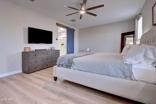 a spacious bedroom with a bed and a flat screen tv