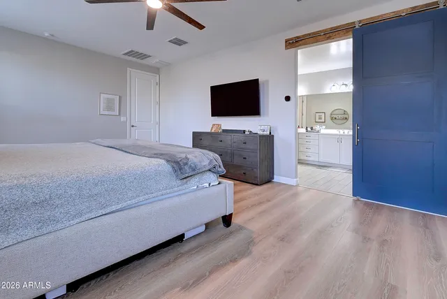 a spacious bedroom with a bed and wooden floor