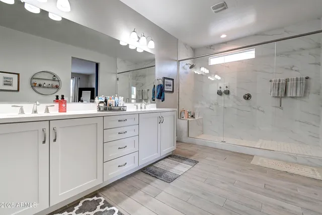 a bathroom with a double vanity sink mirror and shower