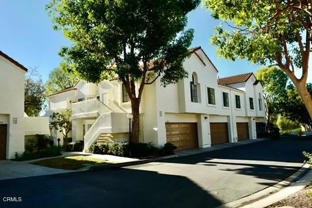 a front view of residential houses with yard and trees