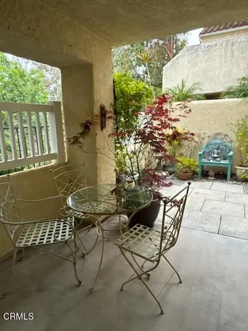 a patio with table and chairs and potted plants