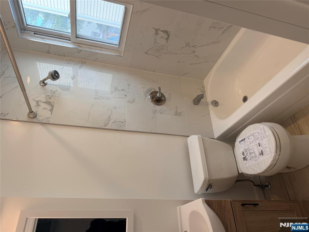 46 High Street Clifton, NJ 07014 - Photo 9 of 14 a white toilet sitting next to a bath tub shower