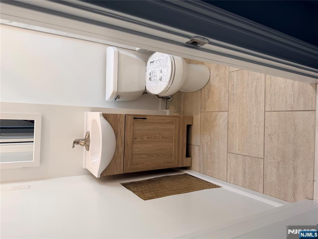 46 High Street Clifton, NJ 07014 - Photo 10 of 14 a bathroom with a sink a toilet and a mirror