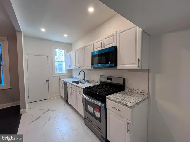a kitchen with a sink stove top oven and white cabinets
