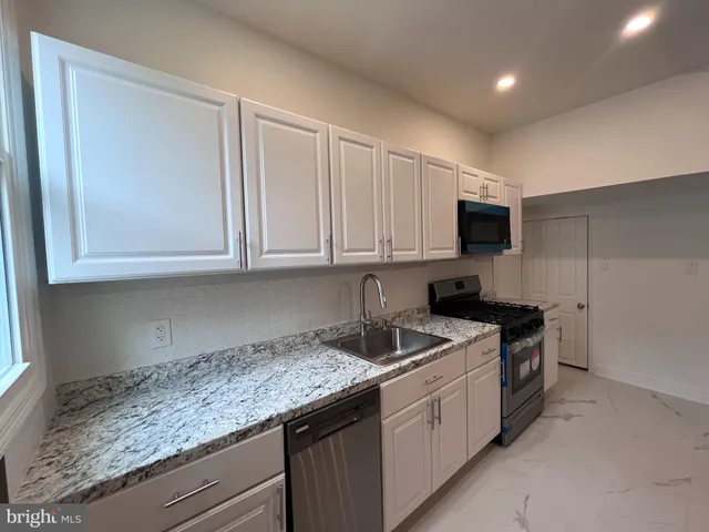 a kitchen with stainless steel appliances granite countertop a sink stove and microwave