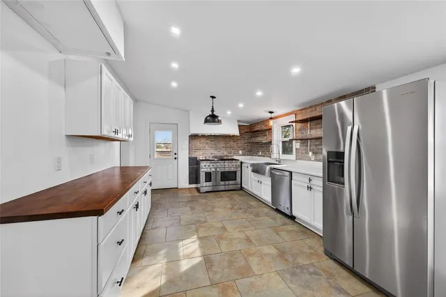 a kitchen with stainless steel appliances granite countertop a sink dishwasher stove top oven and cabinets with wooden floor