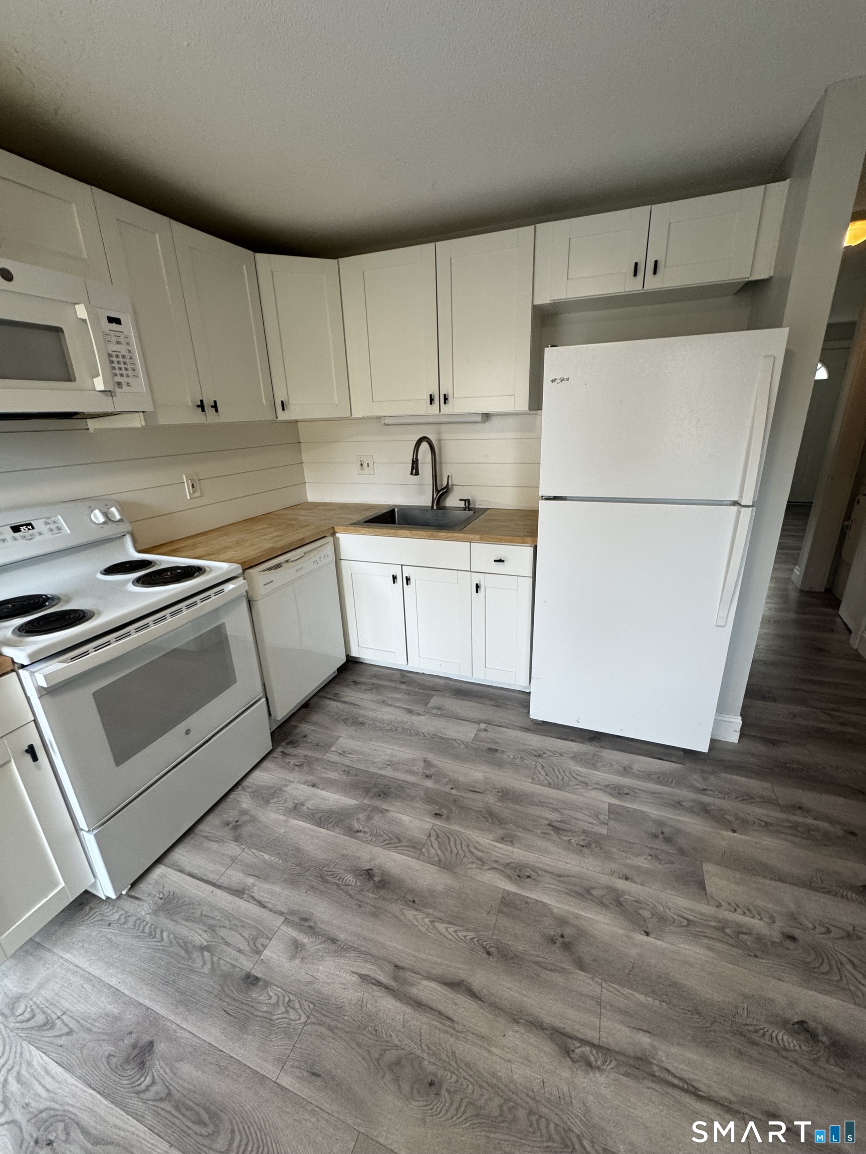 a kitchen with granite countertop white cabinets and white appliances