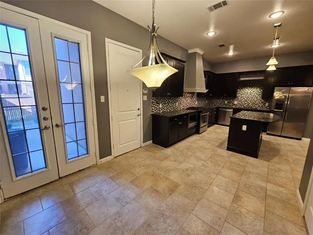 a kitchen with stainless steel appliances granite countertop a stove a refrigerator a sink a microwave oven and a dining table with wooden floor