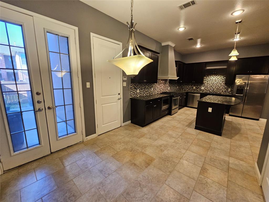 8627 Calvin Road Irving, TX 75063 - Photo 14 of 33 a kitchen with stainless steel appliances granite countertop a stove a refrigerator a sink a microwave oven and a dining table with wooden floor
