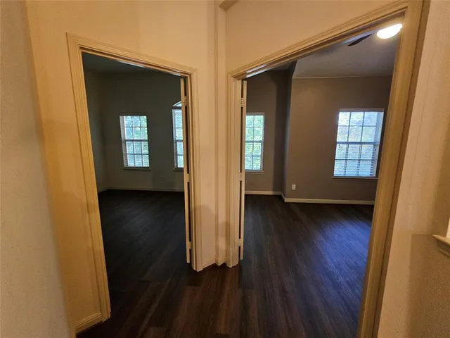 an empty room with wooden floor and windows