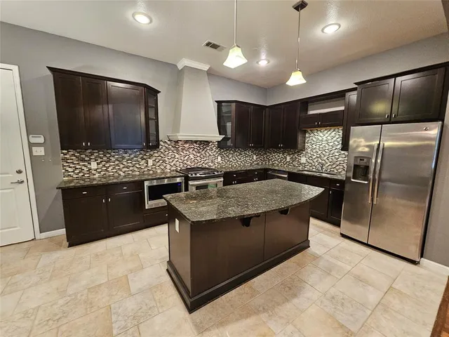 a kitchen with stainless steel appliances granite countertop a sink and a refrigerator
