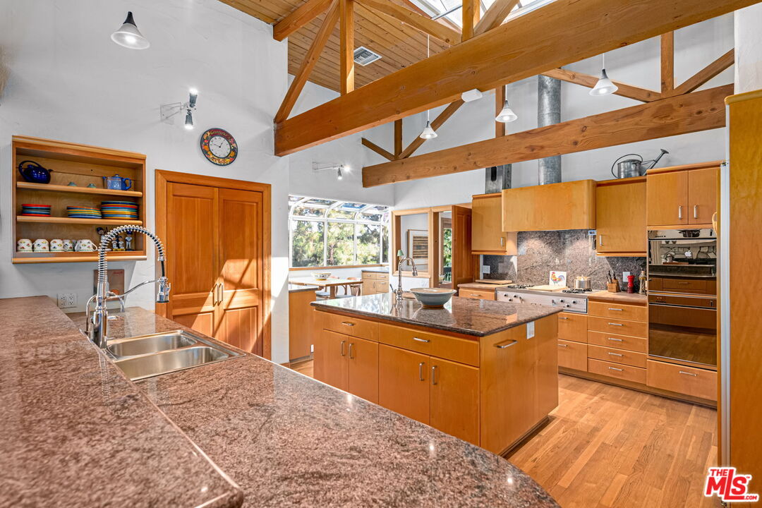 13360 Chalon Road Los Angeles, CA 90049 - Photo 21 of 69 a kitchen with stainless steel appliances kitchen island granite countertop dining table chairs and a large window