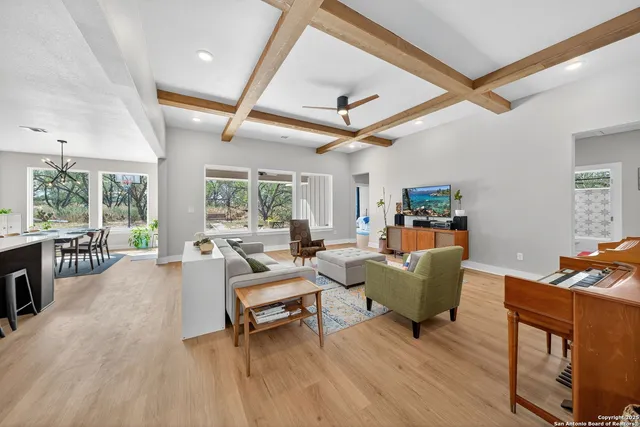 a living room with furniture a ceiling fan and a large window