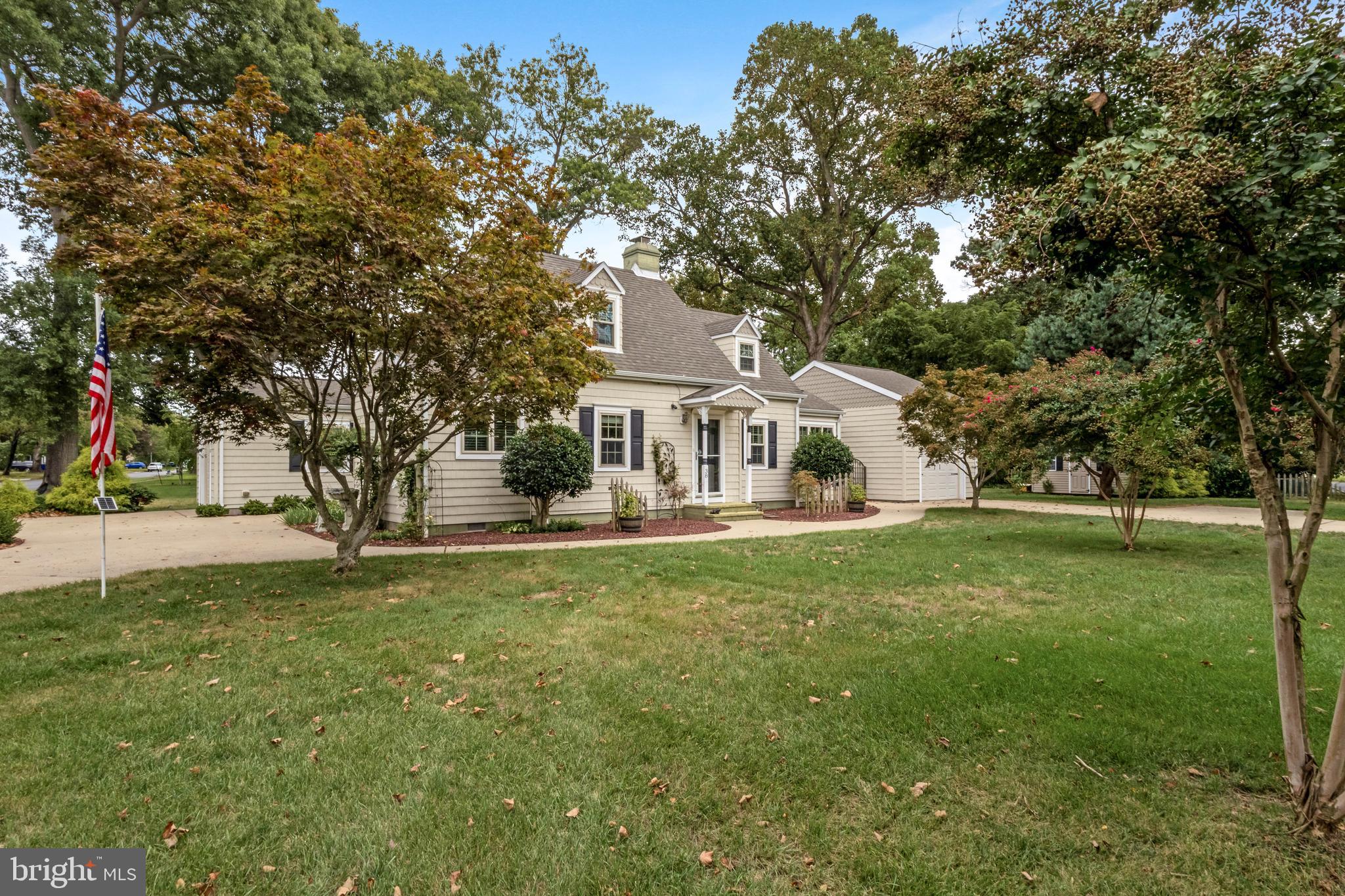 a white house with a big yard and large trees