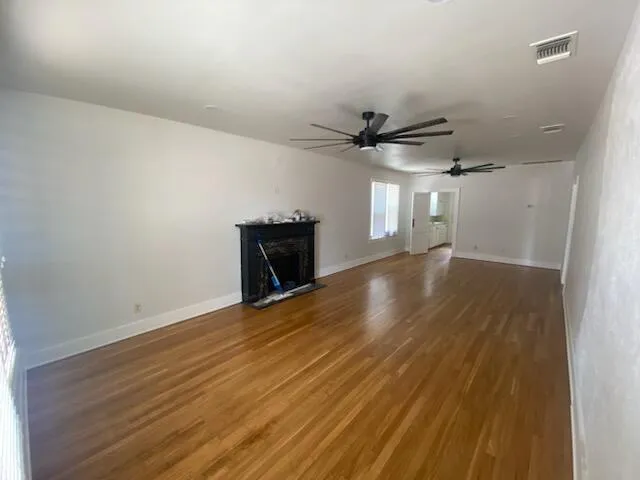 an empty room with wooden floor and a ceiling fan