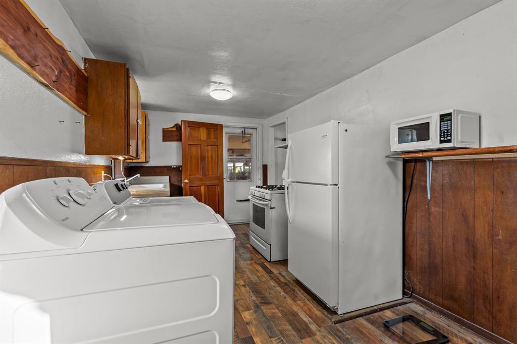 205 College Street Chico, TX 76431 - Photo 13 of 40 Kitchen with brown cabinets, white appliances, dark wood-style flooring, washing machine and clothes dryer, and wainscoting