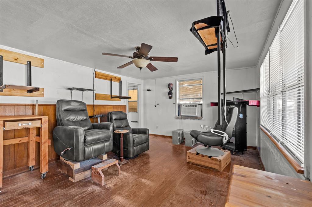 205 College Street Chico, TX 76431 - Photo 15 of 40 Living area with dark wood-style flooring, a textured ceiling, ceiling fan, and wooden walls