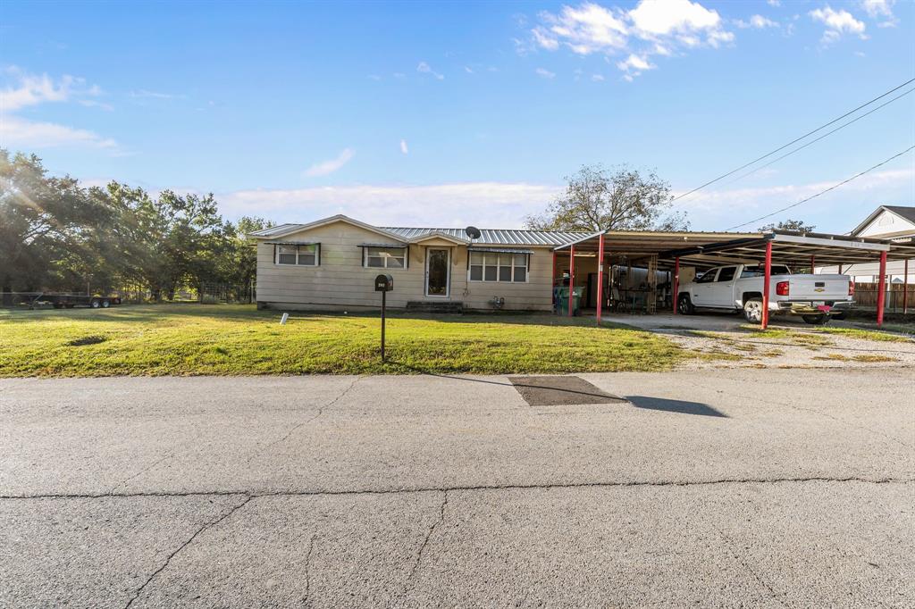 205 College Street Chico, TX 76431 - Photo 8 of 40 Ranch-style house with a front yard, an attached carport, driveway, and a metal roof