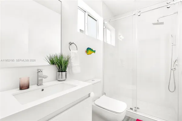 a bathroom with a granite countertop sink a toilet and shower