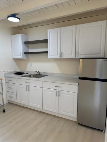 a kitchen with white cabinets and refrigerator